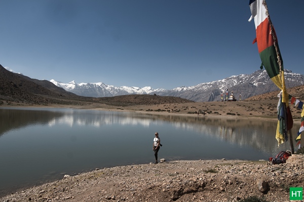 Dhankar Lake with prayer flags and a trekker—classic short hike on a Spiti road trip, above Dhankar Monastery.
