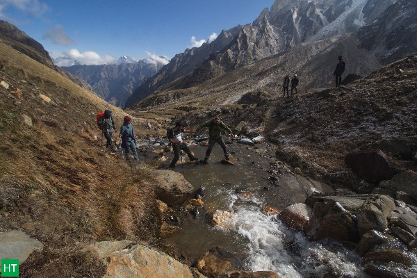 Trekkers crossing a mountain stream on the Kedartal trail in Uttarakhand.